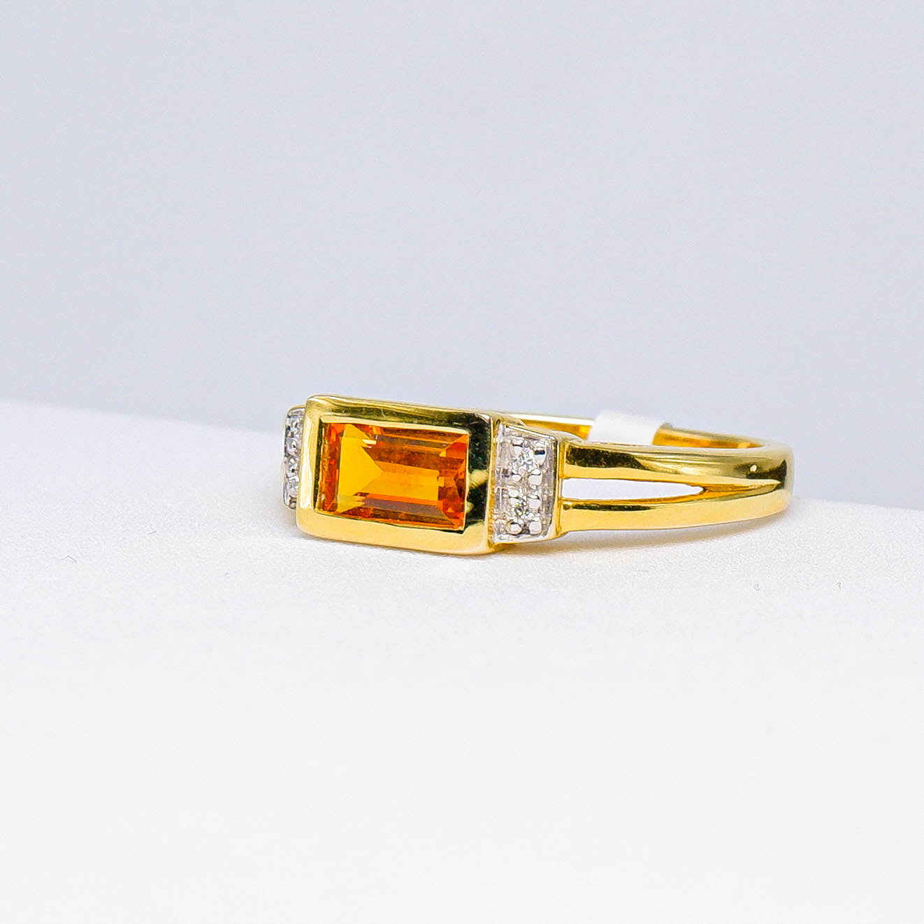 Gold ring with rectangular orange gemstone and small white accent stones, fine jewelry