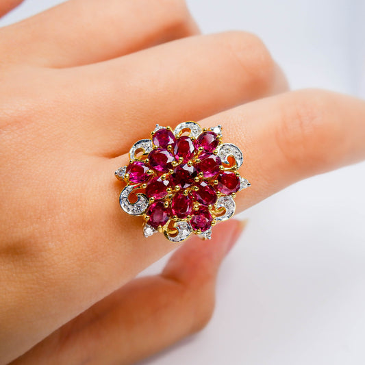 Gold and silver ring with cluster of natural red gemstones and diamonds on a finger