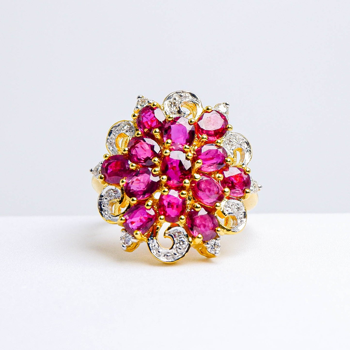 Gold ring with cluster of oval red gemstones and diamond accents in floral design