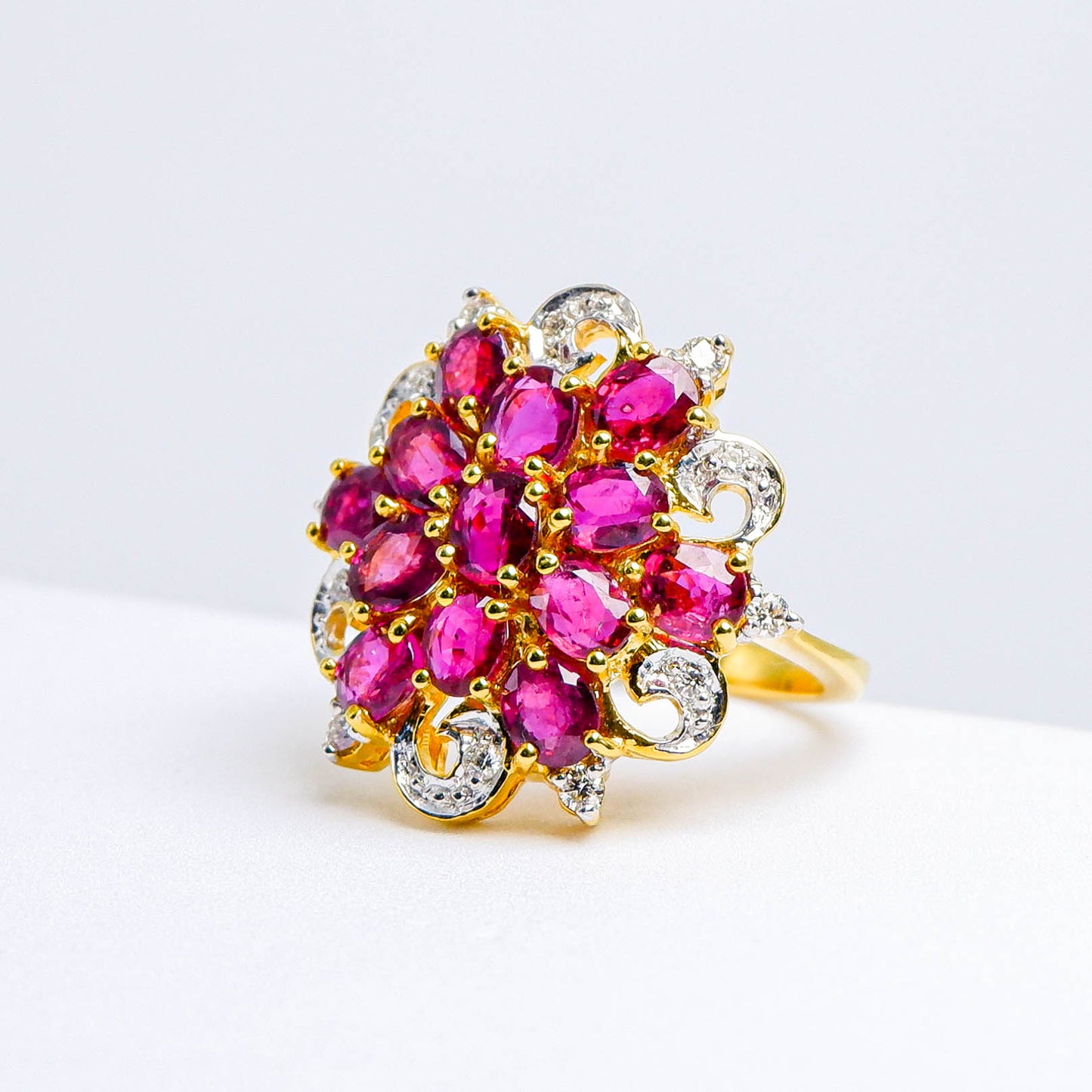 Gold ring with vivid red gemstones and sparkling white accents, floral cluster design