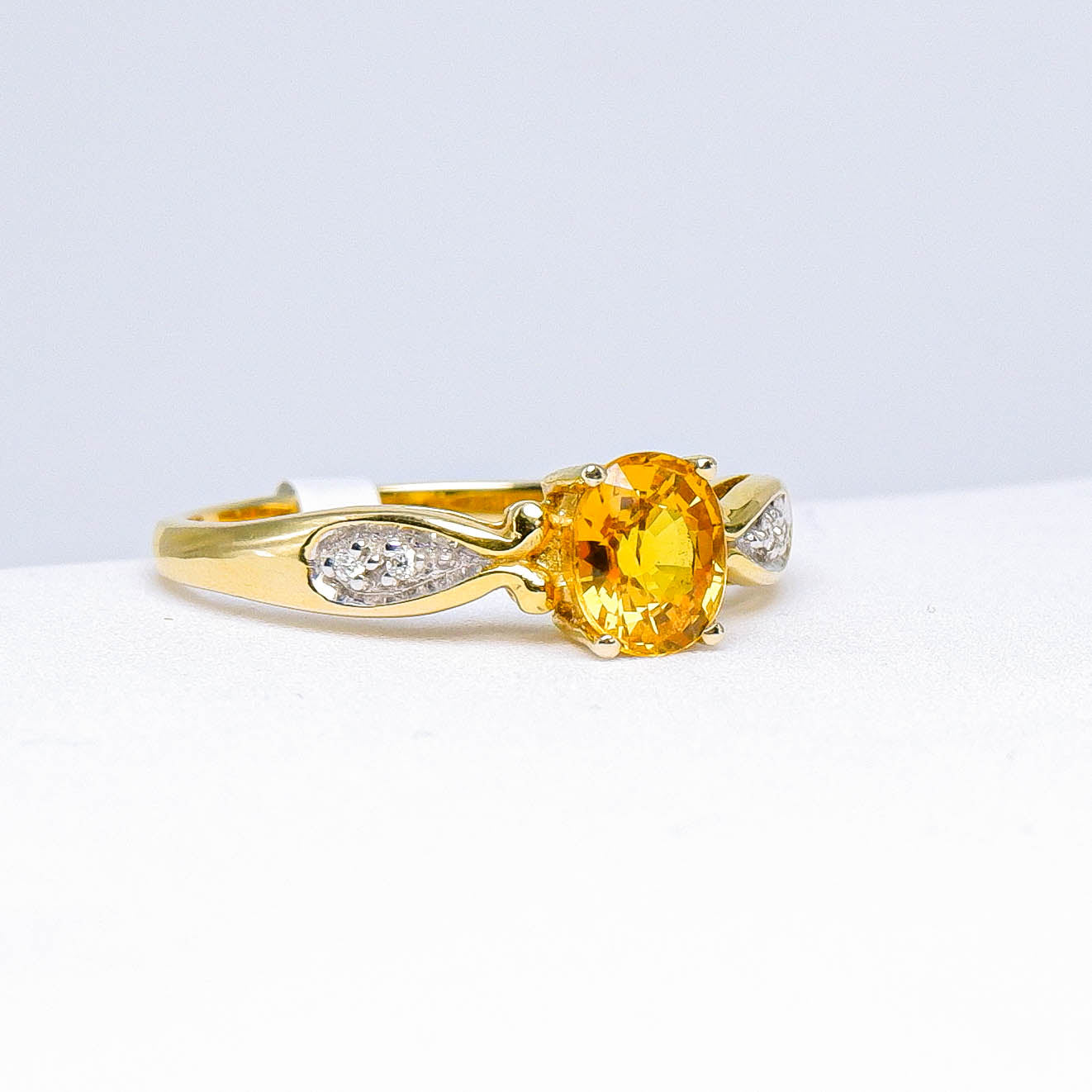 Gold ring with oval yellow sapphire and small diamonds, elegant fine jewelry on white background