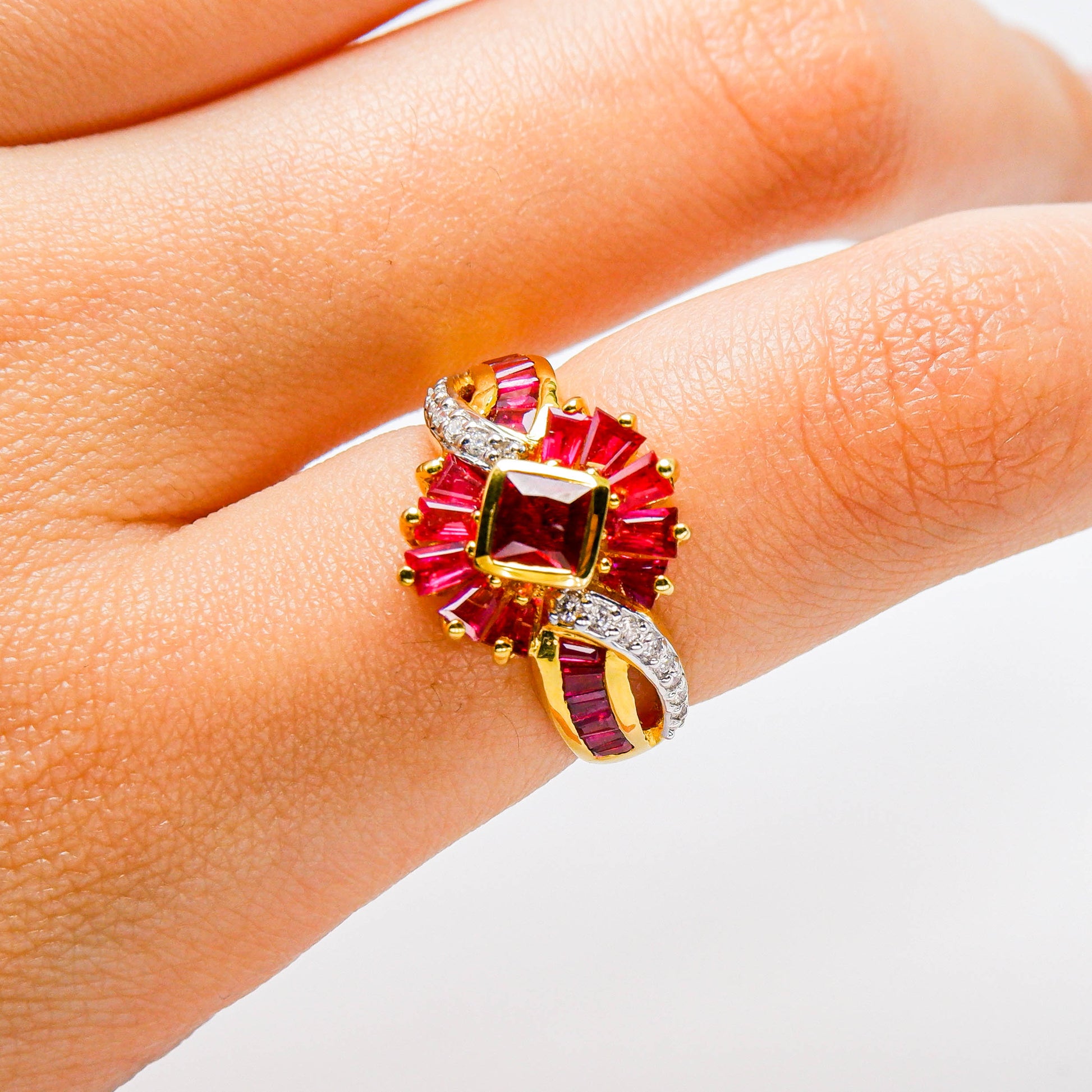 Gold ring with red gemstones and diamond accents on a finger, fine jewelry close-up