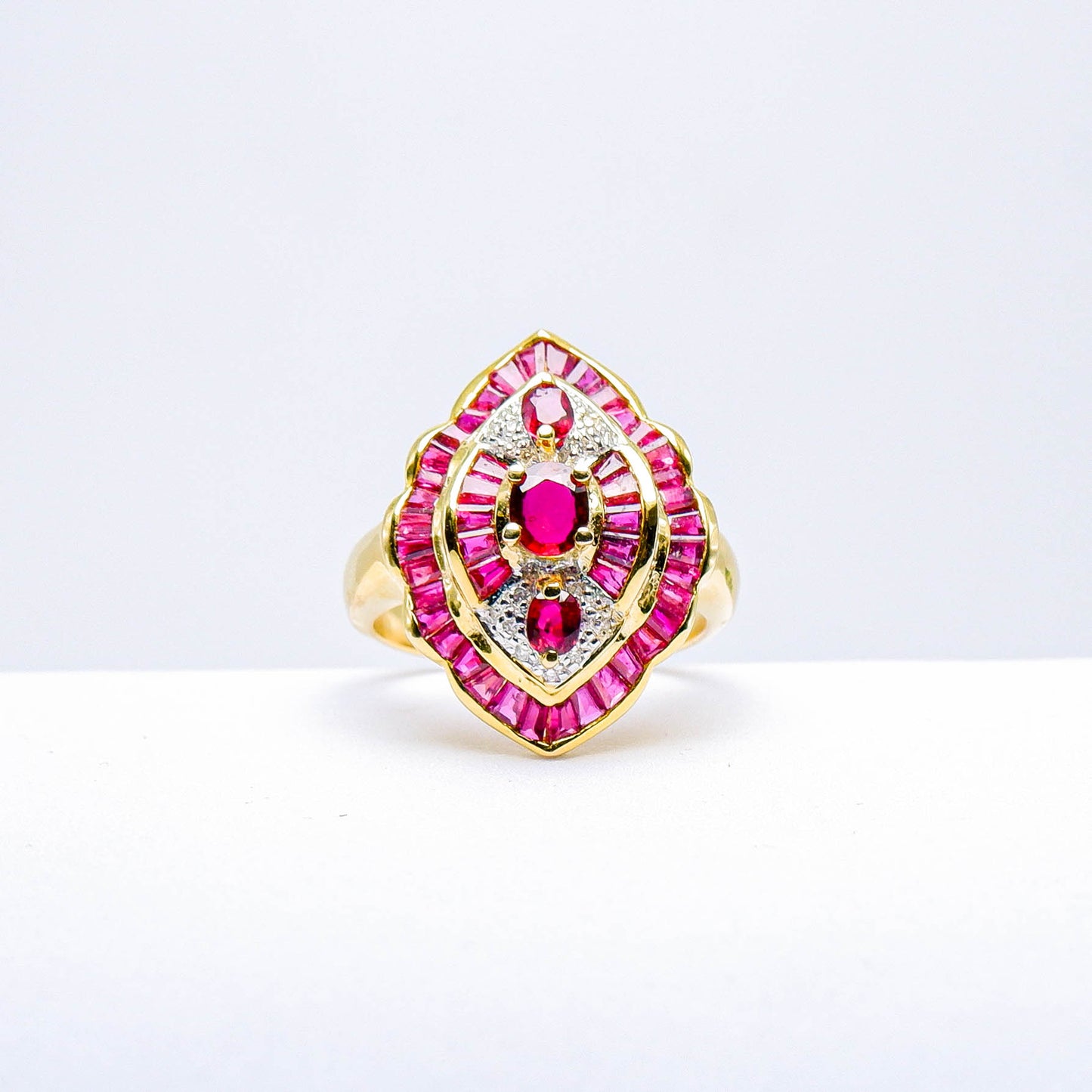 Gold ring with natural red gemstones and diamond accents on a white background