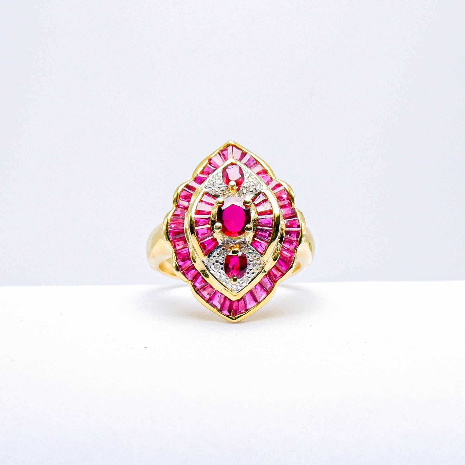 Gold ring with natural red gemstones and diamond accents on a white background