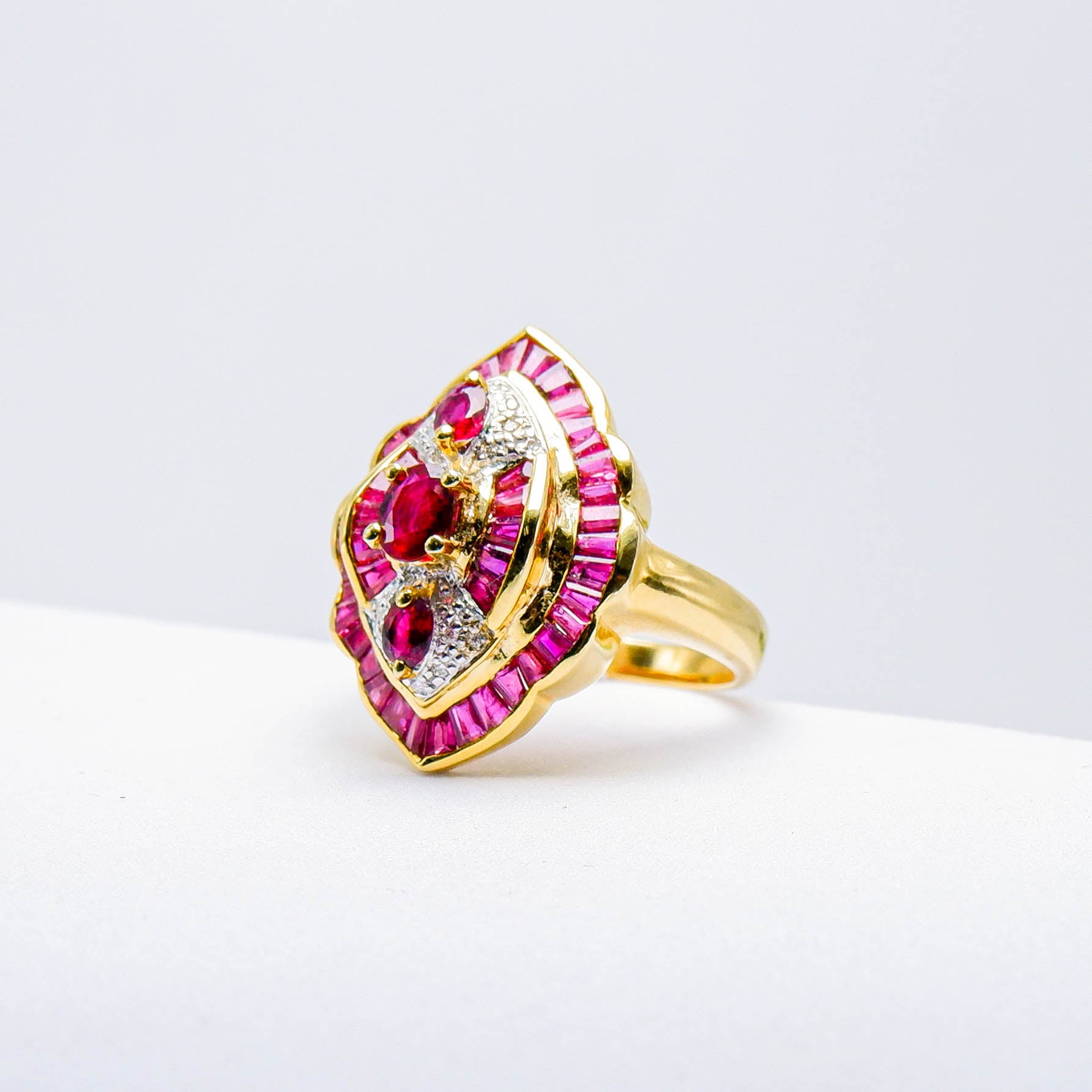 Gold ring with natural red gemstones and diamond accents on white background