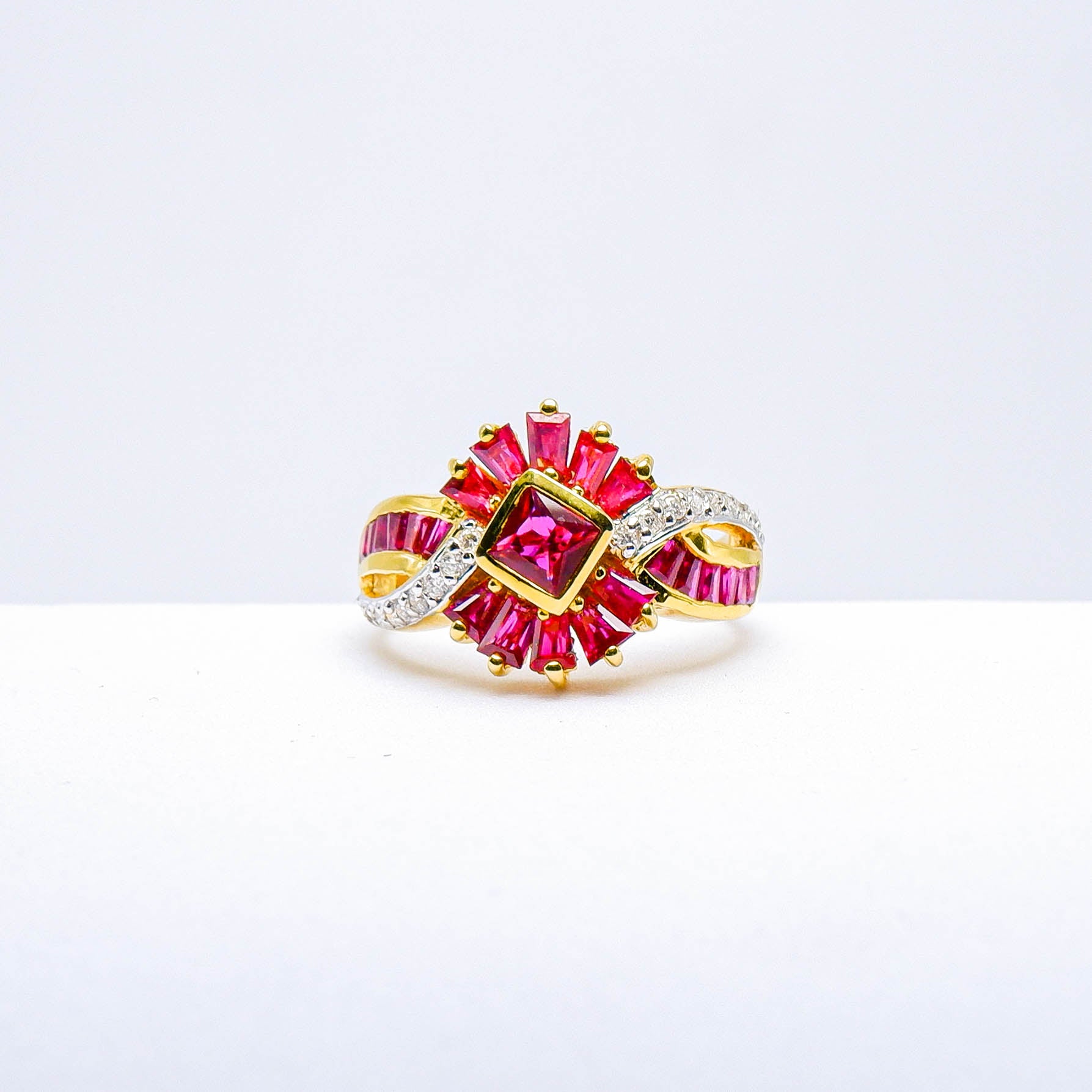 Gold ring with square and baguette cut pink gemstones and diamond accents on white background