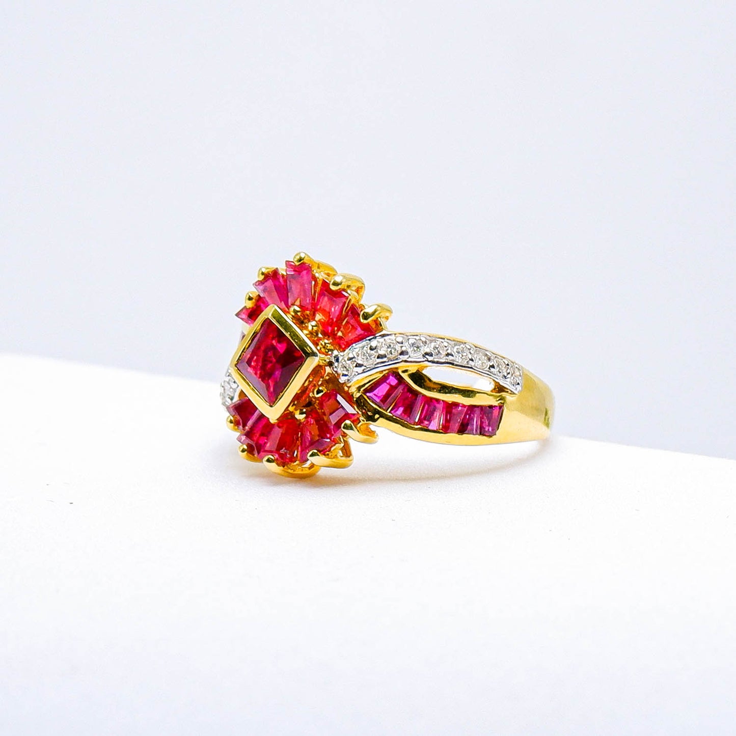 Gold ring with red gemstones and diamond accents on white background