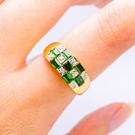 Gold ring with square green gemstones and diamonds on a finger, luxury jewelry design